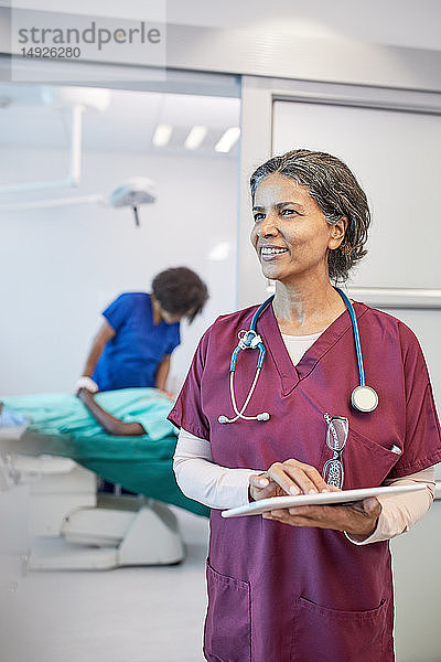 Selbstbewusste  lächelnde Ärztin mit digitalem Tablet in der Klinik