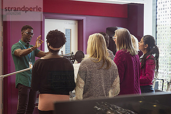 Männlicher Dirigent leitet Frauen beim Singen im Aufnahmestudio