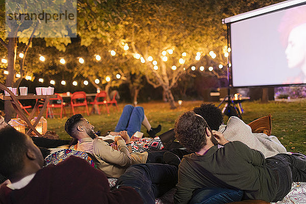 Freunde entspannen sich  schauen einen Film auf der Projektionsfläche im Hinterhof