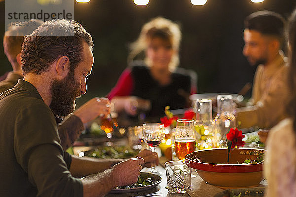 Freunde genießen das Abendessen auf einer Gartenparty