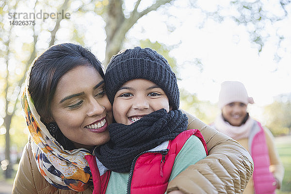 Porträt einer glücklichen muslimischen Mutter im Hidschab  die ihren Sohn im Herbst im Park umarmt