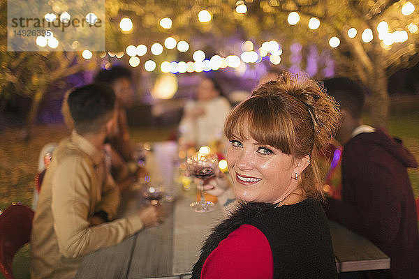 Porträt einer glücklichen Frau beim Abendessen auf einer Gartenparty