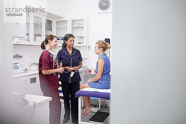 Ärztin und Krankenschwester im Gespräch mit einer Patientin im Untersuchungsraum einer Klinik