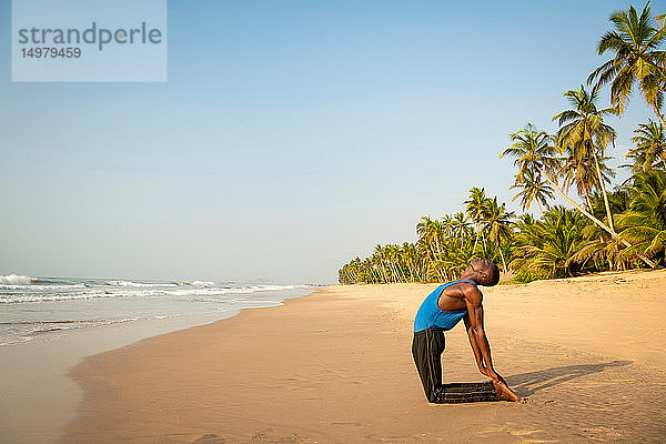 Mann praktiziert Yoga am Strand