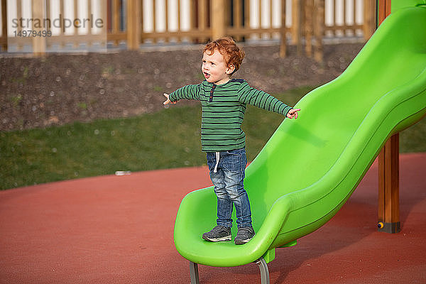 Junge spielt auf einer Rutsche auf dem Spielplatz