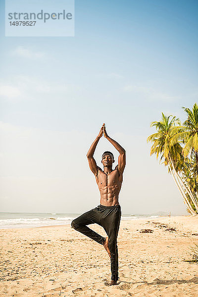 Mann praktiziert Yoga am Strand