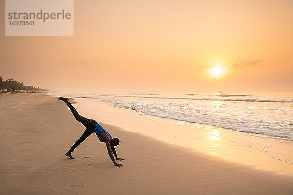 Mann praktiziert Yoga am Strand