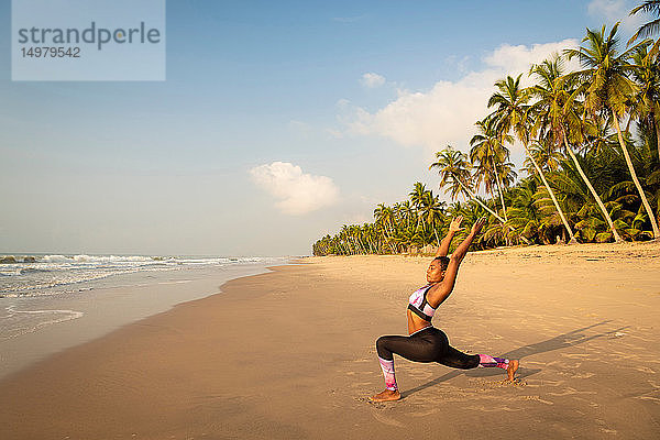 Frau praktiziert Yoga am Strand