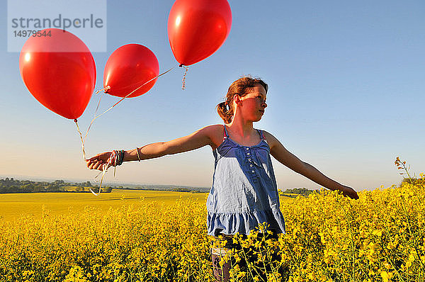 Mädchen mit roten Luftballons auf Rapsfeld  Eastbourne  East Sussex  Vereinigtes Königreich