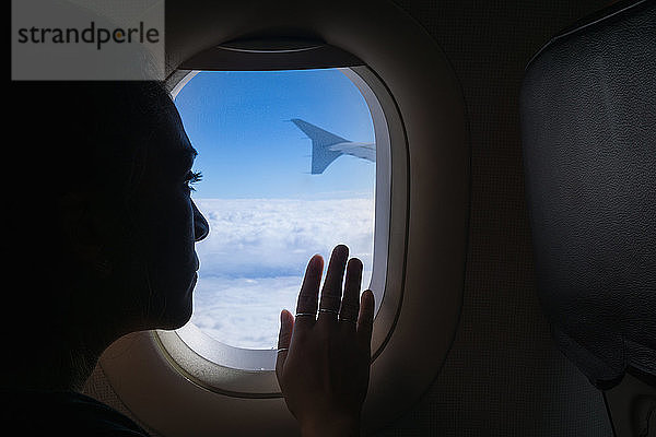 Frau reist im Flugzeug und schaut aus dem Fenster