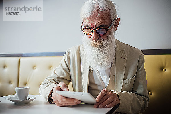 Leitender Geschäftsmann benutzt digitales Tablett im Café