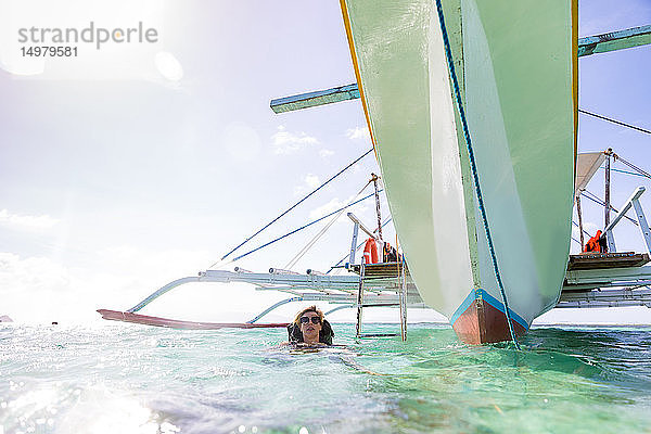 Frau schwimmt in der Nähe eines vertäuten Bootes  Insel Ginto  Linapacan  Philippinen