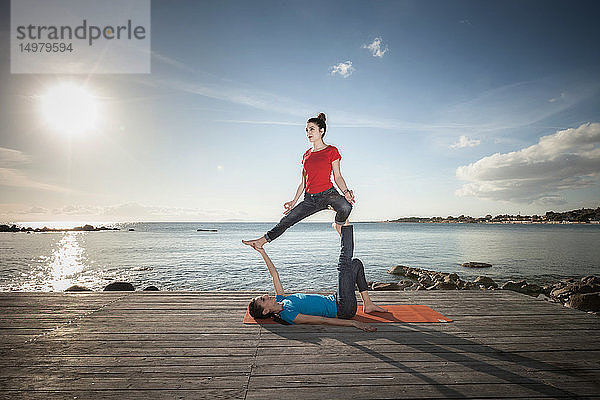 Frauen praktizieren Akro-Yoga am Meer