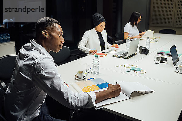 Geschäftsteam bereitet Notizen für Konferenztisch-Sitzung vor