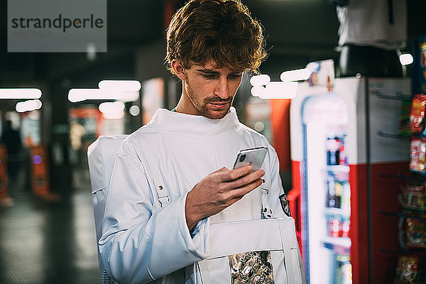 Astronaut mit Smartphone auf dem Bahnsteig