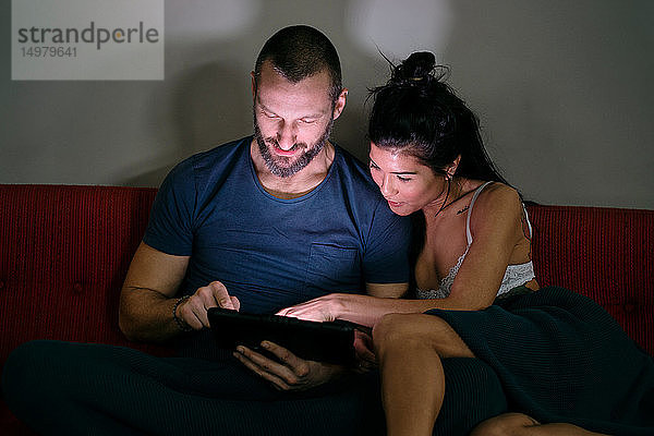 Hipster-Paar mit digitalem Tablett auf dem Sofa