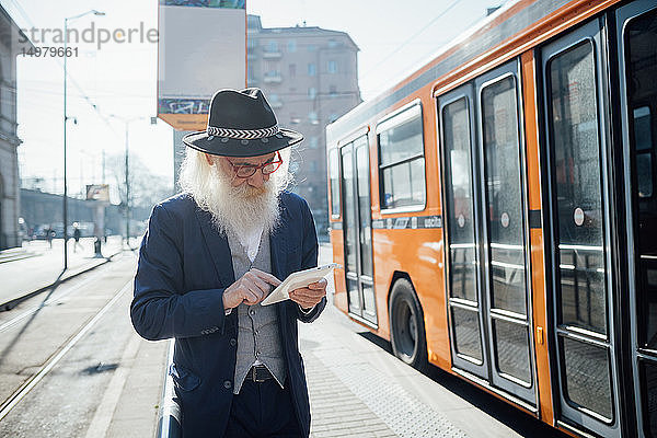 Leitender Geschäftsmann benutzt digitales Tablett neben dem Bus in der Stadt  Mailand  Lombardei  Italien