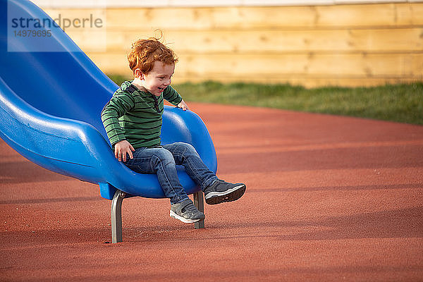 Junge spielt auf einer Rutsche auf dem Spielplatz