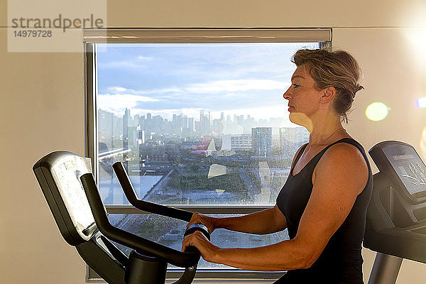 Frau radelt mit dem Fahrrad in Sporthalle mit Blick auf die Stadt  Manila  Philippinen