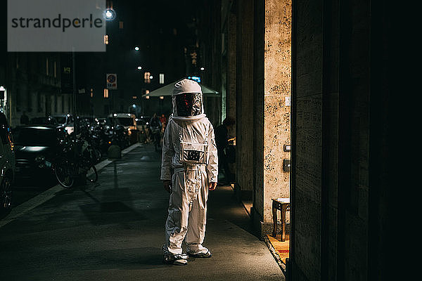 Astronaut geht nachts auf dem Bürgersteig