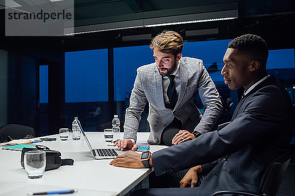 Geschäftsleute schauen während der Sitzung am Konferenztisch auf den Laptop