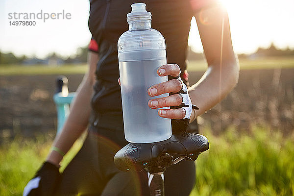 Radfahrerin mit Wasserflasche in der Hand  Mittelteil