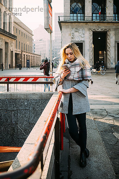 Junge Frau an U-Bahn-Station mit Blick auf Smartphone  Mailand  Italien
