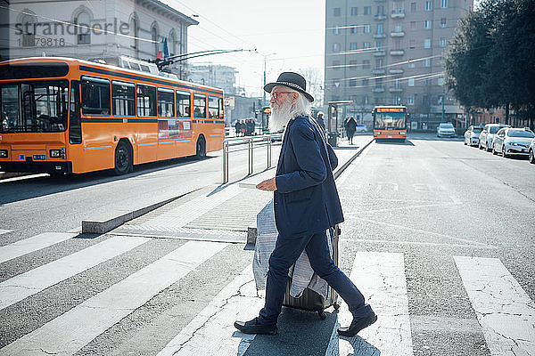 Leitender Geschäftsmann mit Rollgepäck auf einem Fußgängerüberweg  Mailand  Lombardei  Italien