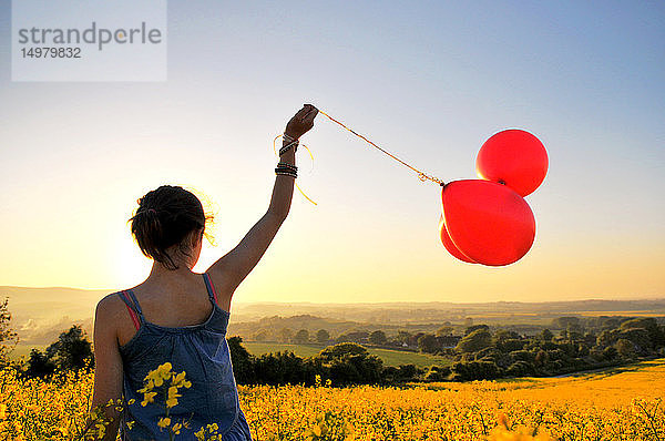 Mädchen mit roten Luftballons auf Rapsfeld  Eastbourne  East Sussex  Vereinigtes Königreich