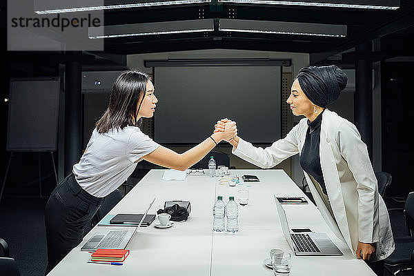 Geschäftsfrauen schütteln Hände über Konferenztisch