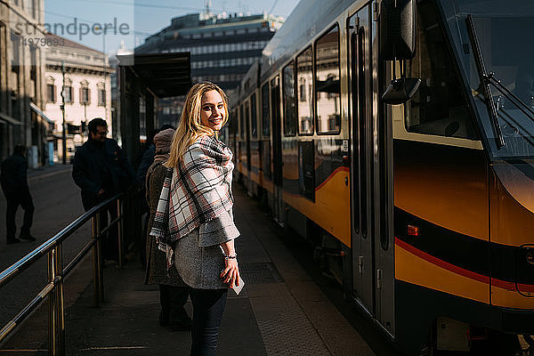 Junge Frau  die in der Straßenbahnhaltestelle über die Schulter schaut  Porträt  Mailand  Italien