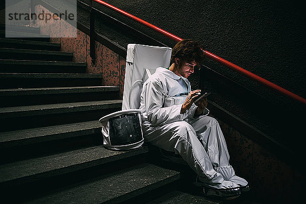 Astronaut mit Smartphone auf der Treppe