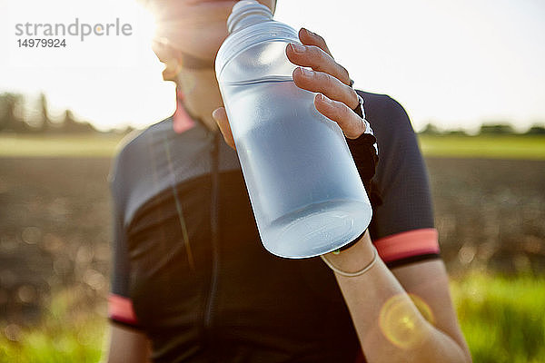 Radfahrerin trinkt aus Wasserflasche  abgeschnitten