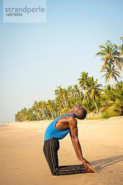 Mann praktiziert Yoga am Strand