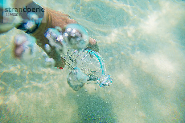 Frau füllt Plastikflasche mit Meerwasser