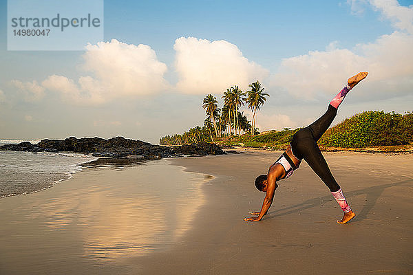 Frau praktiziert Yoga am Strand