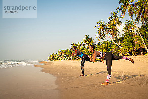 Paar praktiziert Yoga am Strand