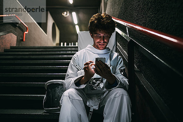 Astronaut mit Smartphone auf der Treppe