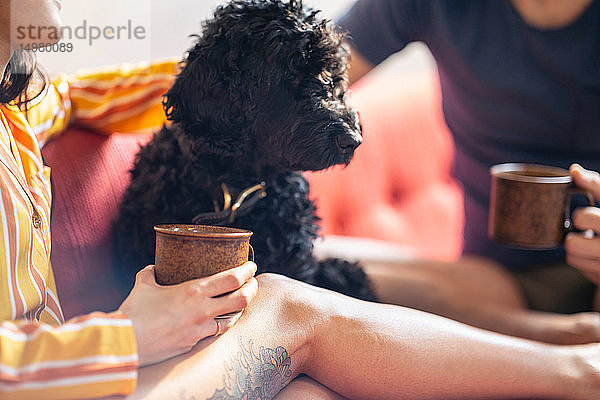 Hipster-Paar beim Kaffee trinken mit Hund auf dem Sofa