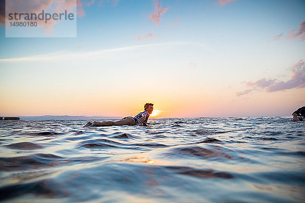 Surfer  der bei Sonnenuntergang im Meer gleitet  Pagudpud  Ilocos Norte  Philippinen