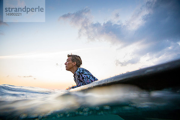 Surfer  der bei Sonnenuntergang im Meer gleitet  Pagudpud  Ilocos Norte  Philippinen