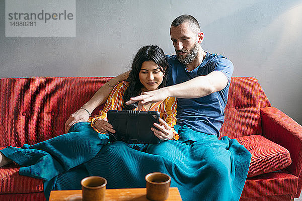 Hipster-Paar mit digitalem Tablett auf dem Sofa