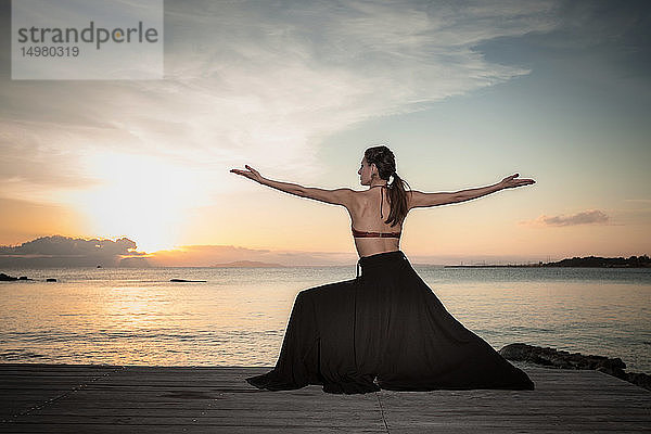 Frau praktiziert Yoga am Meer