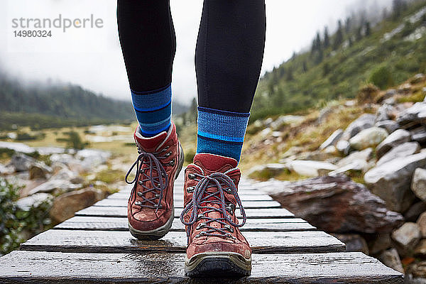 Wanderin  die über einen Holzsteg wandert  Schrägansicht der Beine und Wanderschuhe