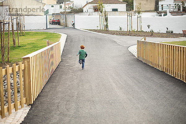 Junge läuft auf Straße in Wohngebiet