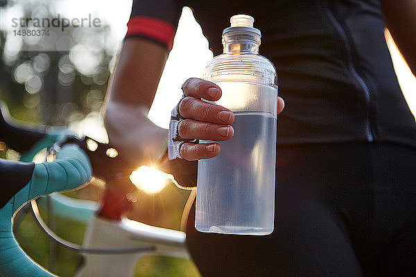 Radfahrerin mit Wasserflasche in der Hand  Mittelteil