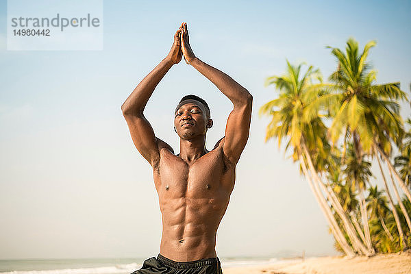 Mann praktiziert Yoga am Strand