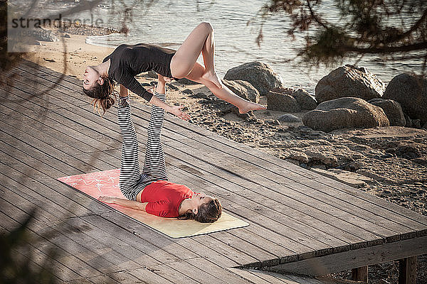 Frauen praktizieren Akro-Yoga am Meer