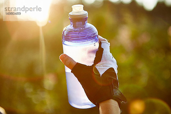 Radfahrerin mit Wasserflasche in der Hand  Nahaufnahme