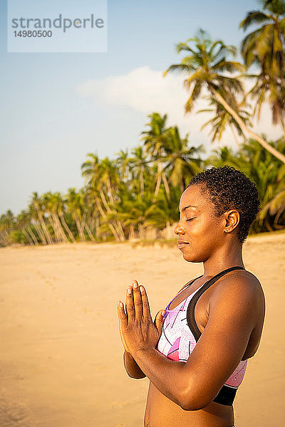 Frau praktiziert Yoga am Strand